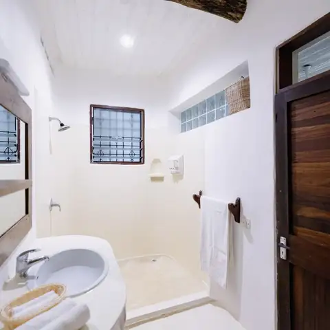 A bright ensuite bathroom with a rustic timber beam