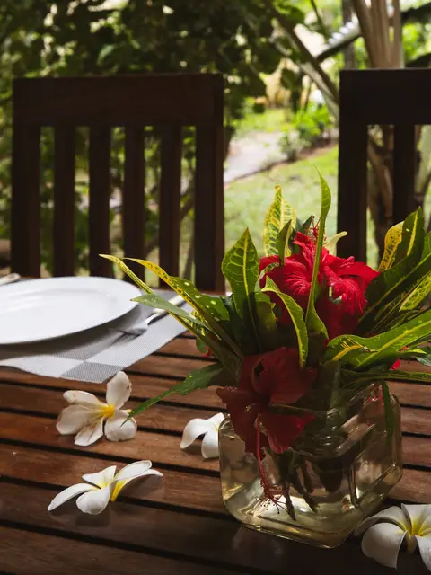 A verandah table set with hibiscus and frangipani